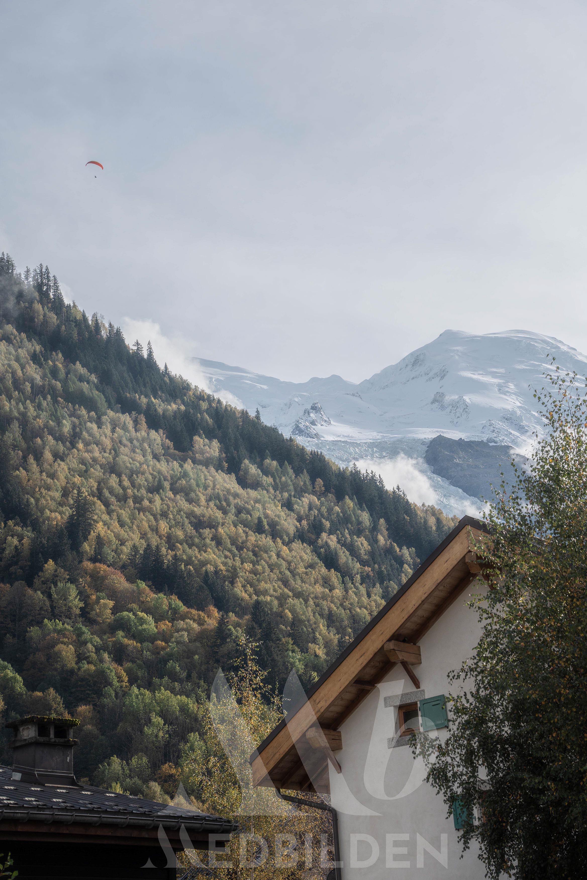 A paraglider crossing in front of the Mont Blanc massif