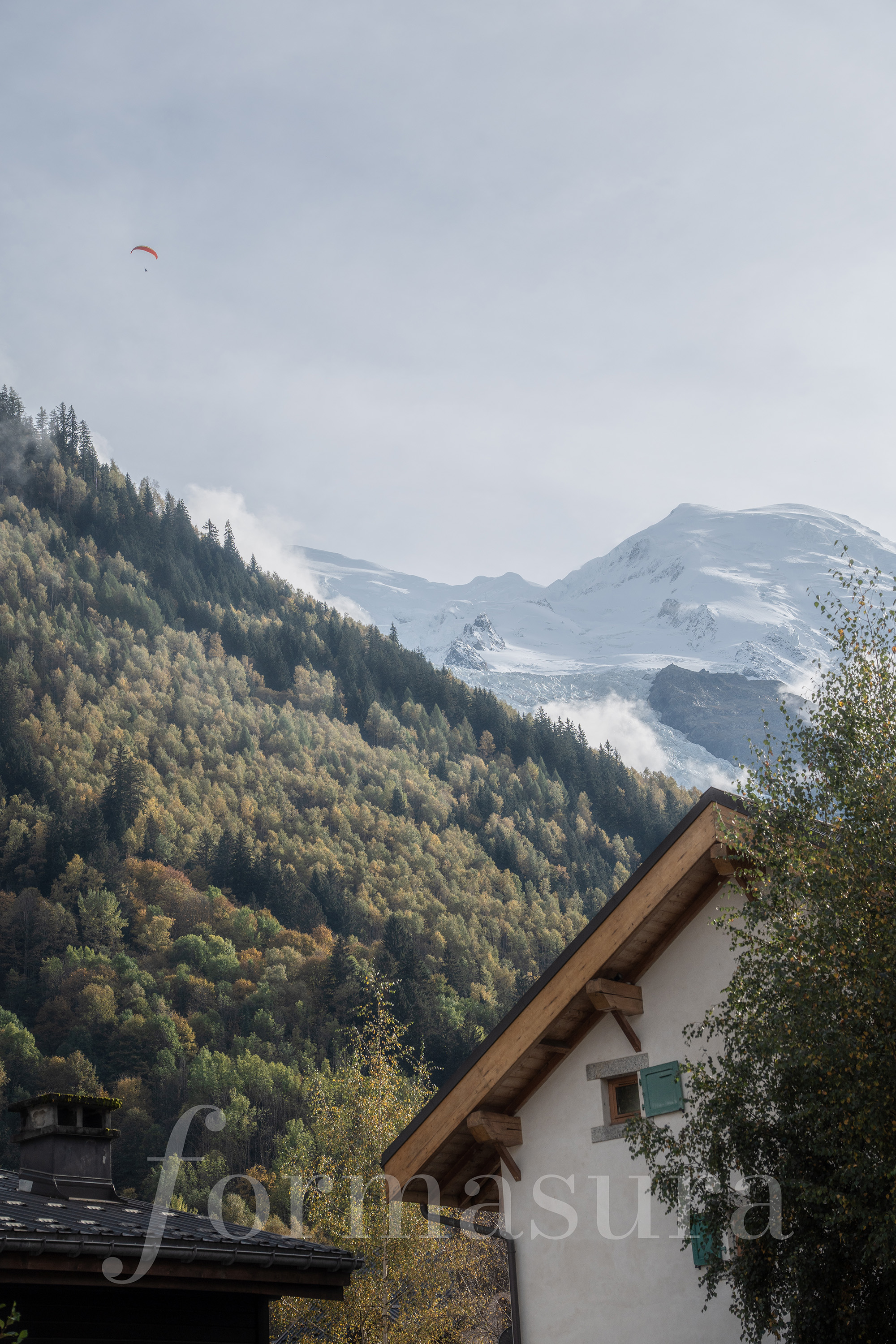 A paraglider crossing in front of the Mont Blanc massif